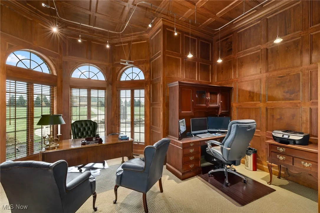 Carpeted office space with a decorative wall, wood walls, coffered ceiling, and a towering ceiling