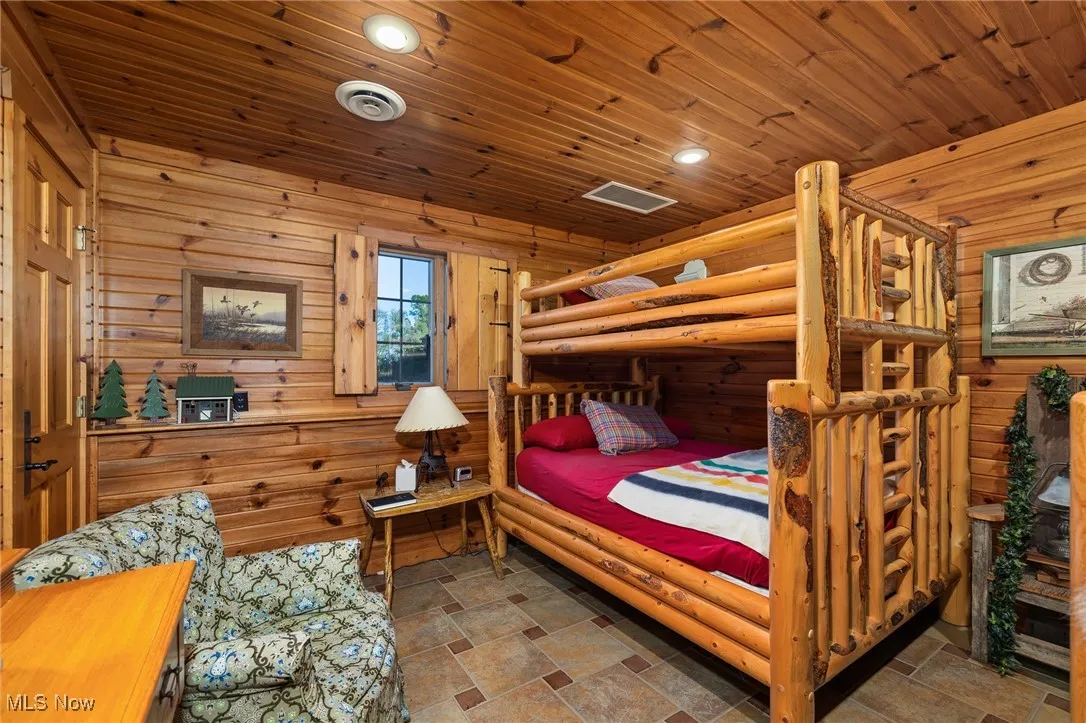 Bedroom featuring visible vents, stone finish flooring, recessed lighting, wooden walls, and wooden ceiling