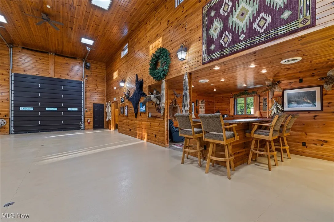 Dining area featuring wooden walls, wooden ceiling, finished concrete flooring, and ceiling fan