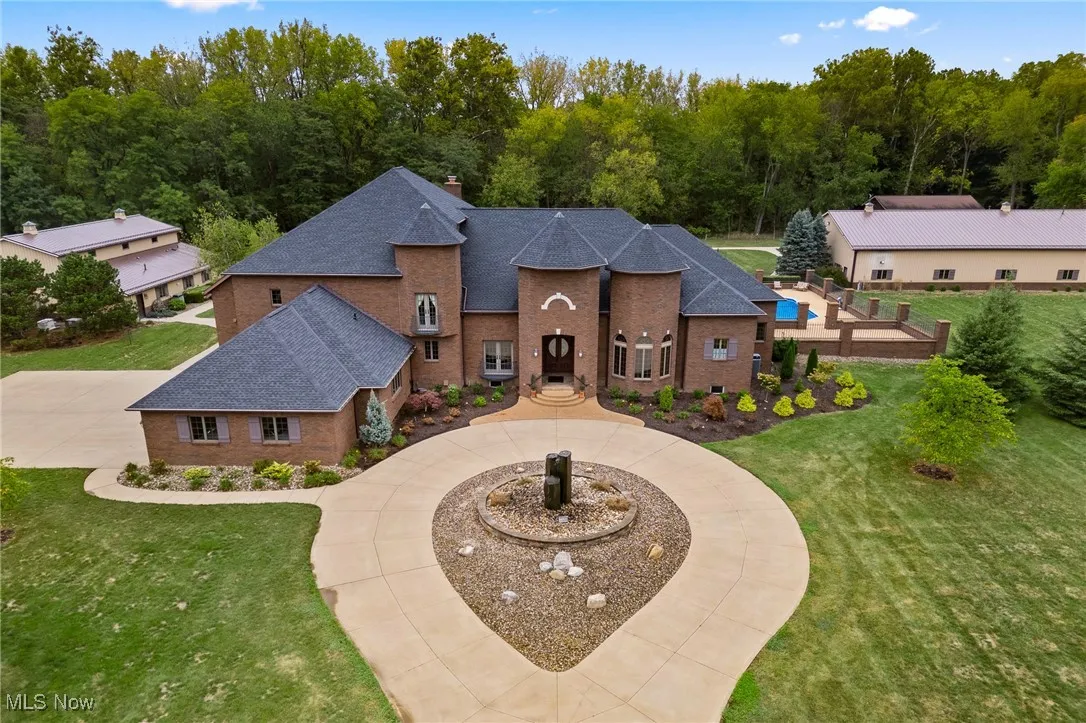 View of front of home with brick siding, curved driveway, a chimney, and a front lawn