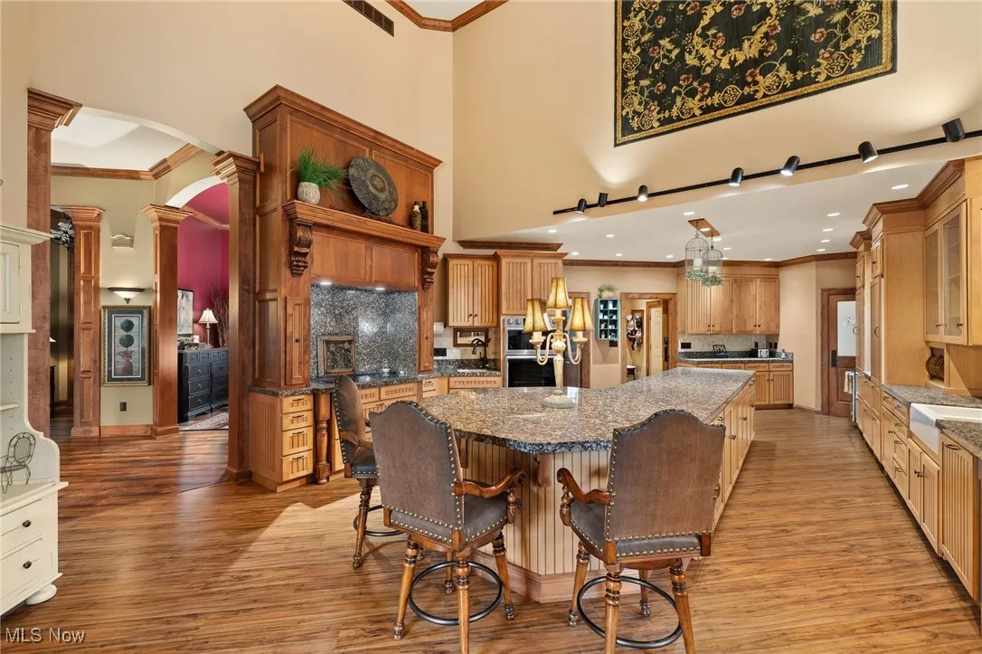 Kitchen featuring visible vents, a large island, light wood-type flooring, a breakfast bar, and arched walkways