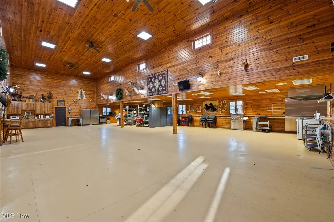 Garage with ceiling fan, a workshop area, wood ceiling, and wood walls