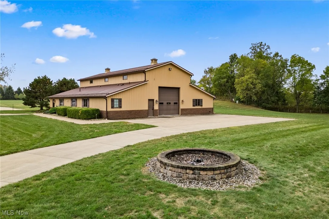 Back of property with driveway, brick siding, a chimney, and a lawn