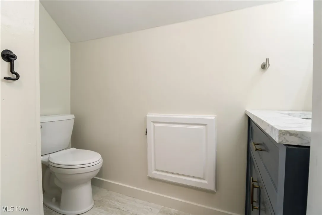 Half Bathroom with vanity, toilet, and baseboards