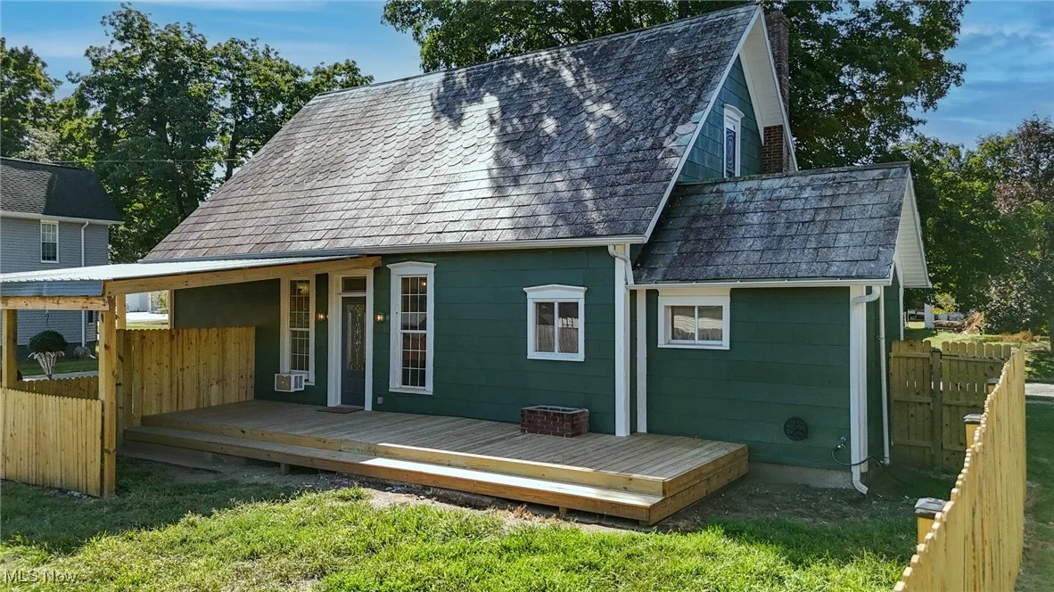 Rear view of property featuring fence and a new wooden deck
