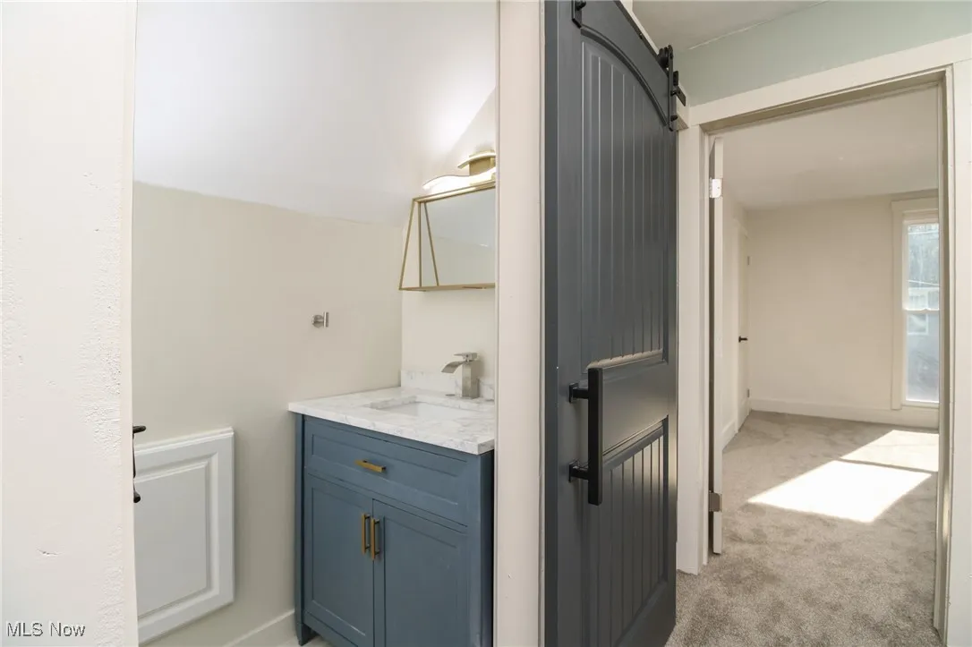Half Bathroom featuring vanity, lofted ceiling, and baseboards