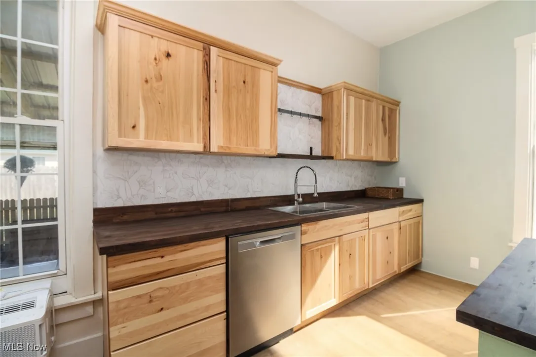 Kitchen featuring a sink, light wood-style floors, dishwasher, and light brown cabinets
