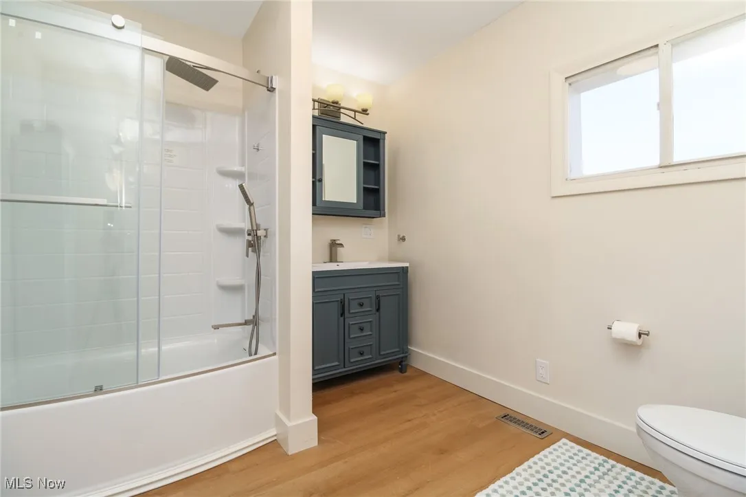 Full bath with baseboards, toilet, wood finished floors, and tasteful vanity