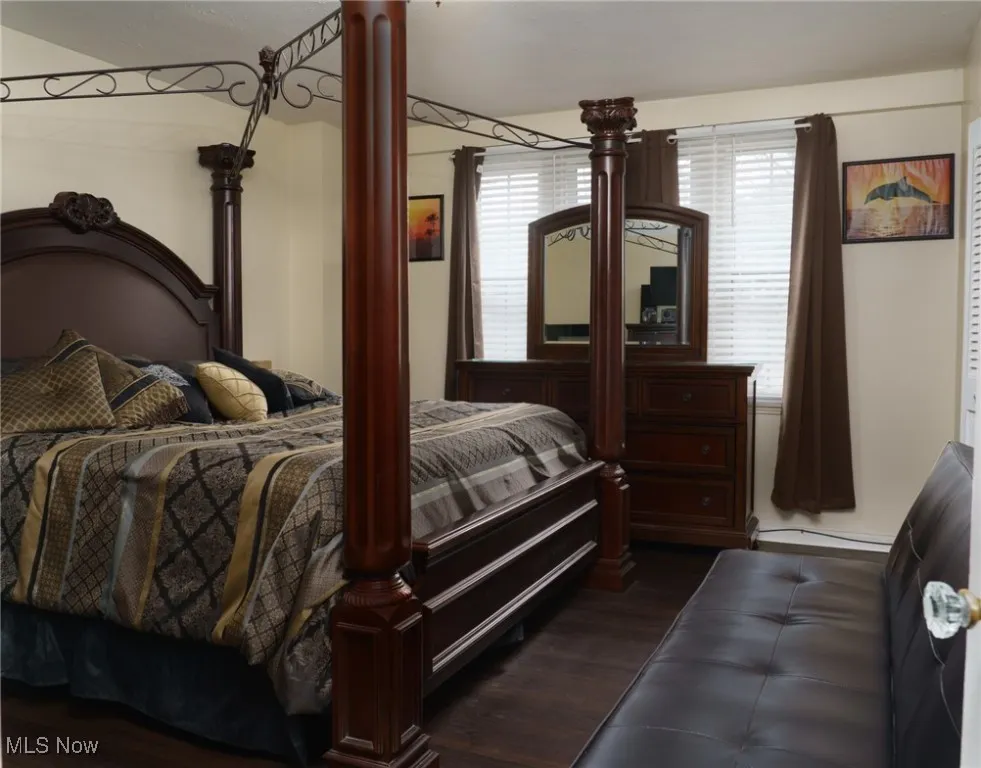 Bedroom featuring baseboard heating, ornate columns, and dark wood-style flooring