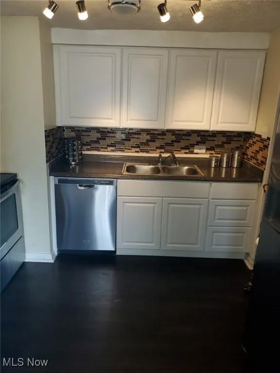 Kitchen with a sink, dark countertops, white cabinets, and stainless steel appliances