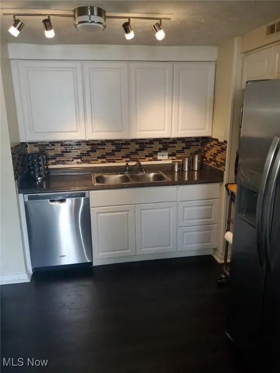 Kitchen featuring a sink, white cabinets, dark wood-style flooring, and stainless steel appliances