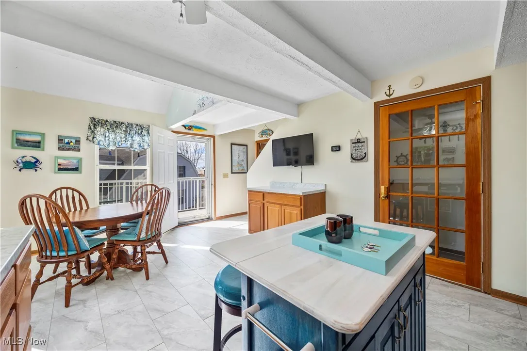 Dining room with beam ceiling, baseboards, marble finish floor, and a textured ceiling