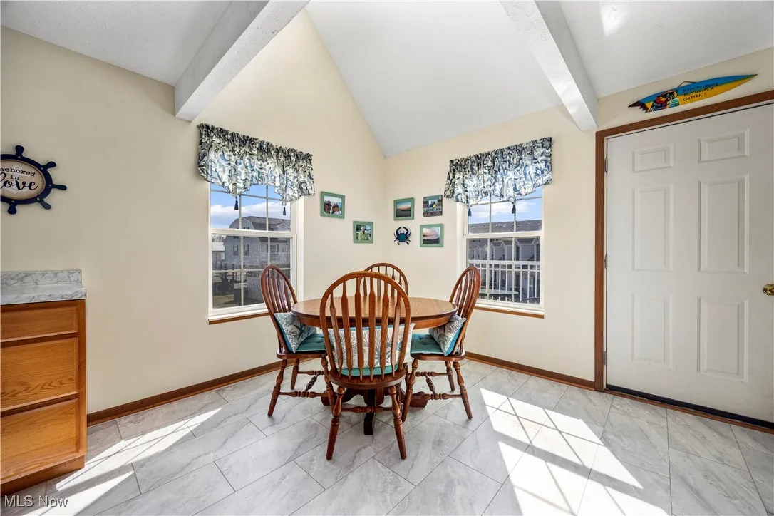 Dining room with lofted ceiling with beams, baseboards, and a wealth of natural light