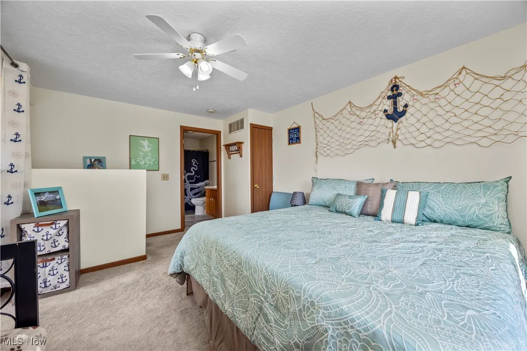 Carpeted bedroom with visible vents, ceiling fan, a textured ceiling, and baseboards