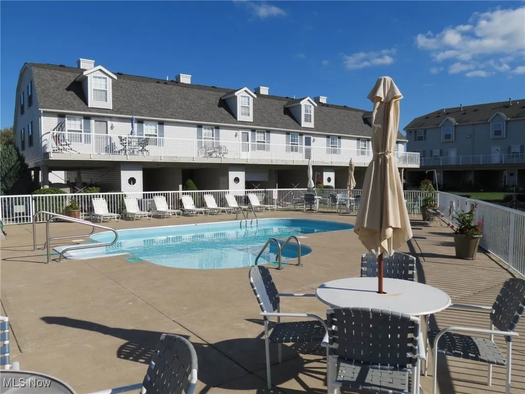 Community pool featuring a patio area, fence, and a residential view