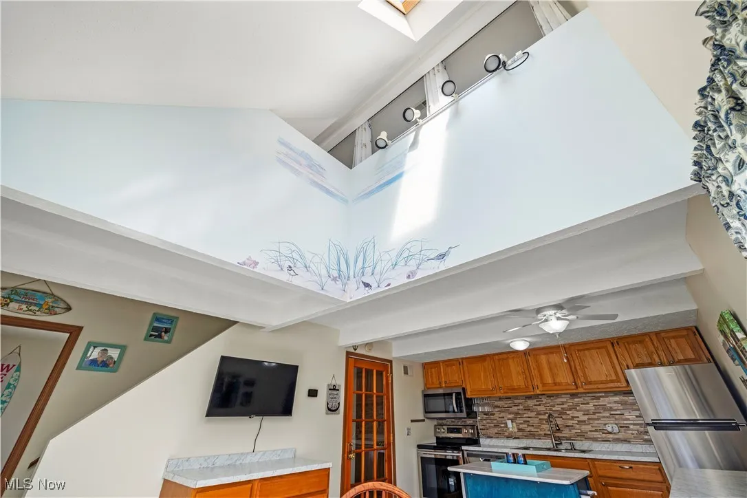 Kitchen with light countertops, brown cabinetry, tasteful backsplash, and appliances with stainless steel finishes