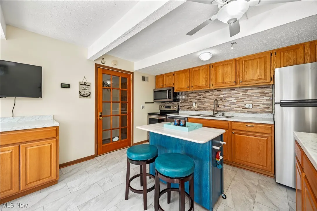 Kitchen with a sink, stainless steel appliances, brown cabinetry, and light countertops