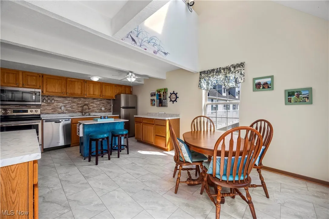 Dining room featuring beamed ceiling, a ceiling fan, and baseboards