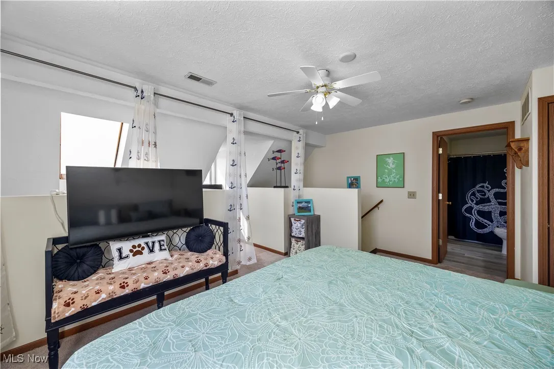 Bedroom featuring baseboards, a ceiling fan, visible vents, and a textured ceiling