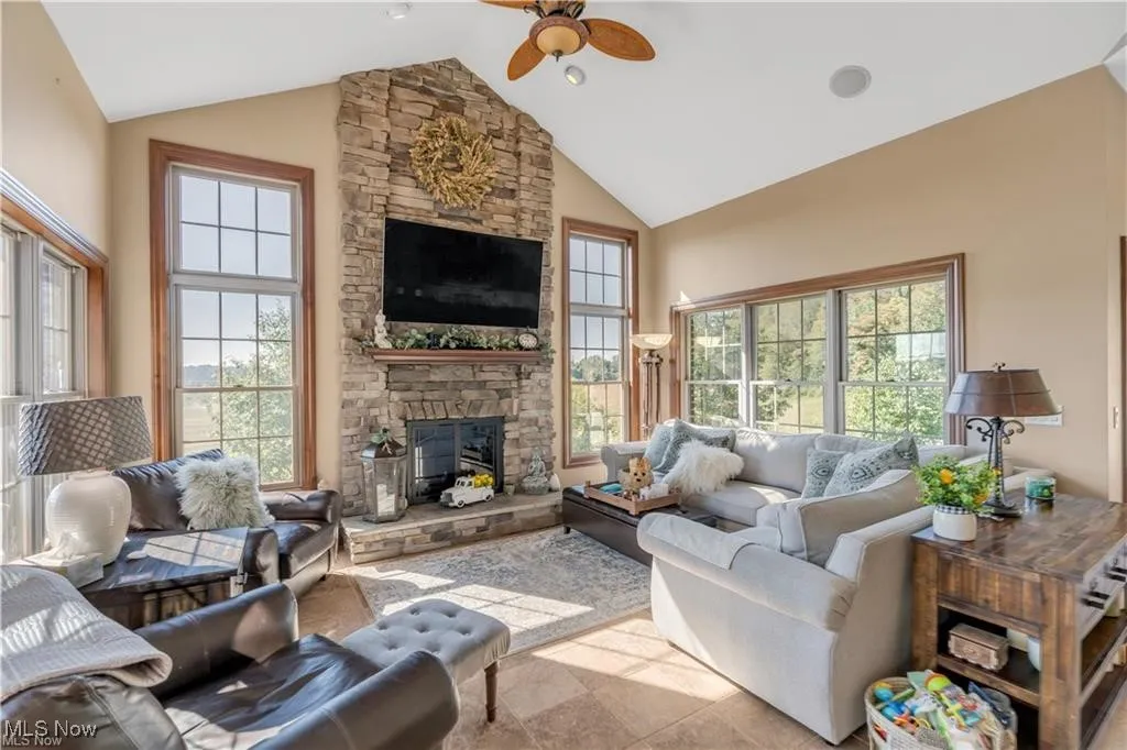 Living area featuring a healthy amount of sunlight, a fireplace, high vaulted ceiling, and ceiling fan