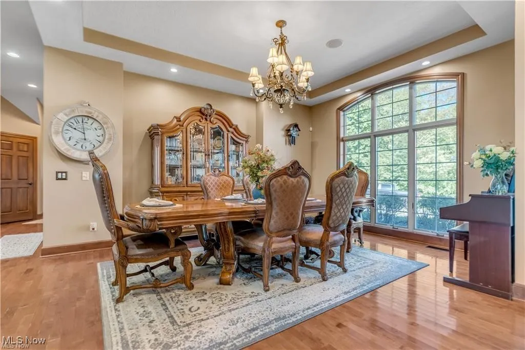 Dining space with a tray ceiling, an inviting chandelier, and wood finished floors