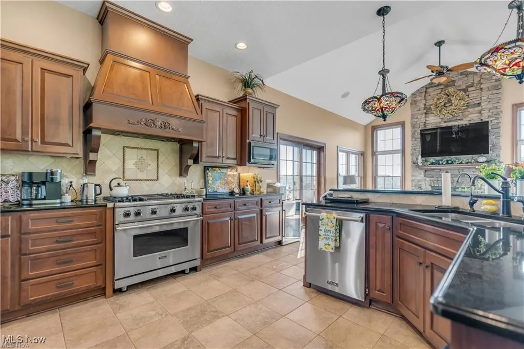 Kitchen featuring dark countertops, appliances with stainless steel finishes, lofted ceiling, and a sink