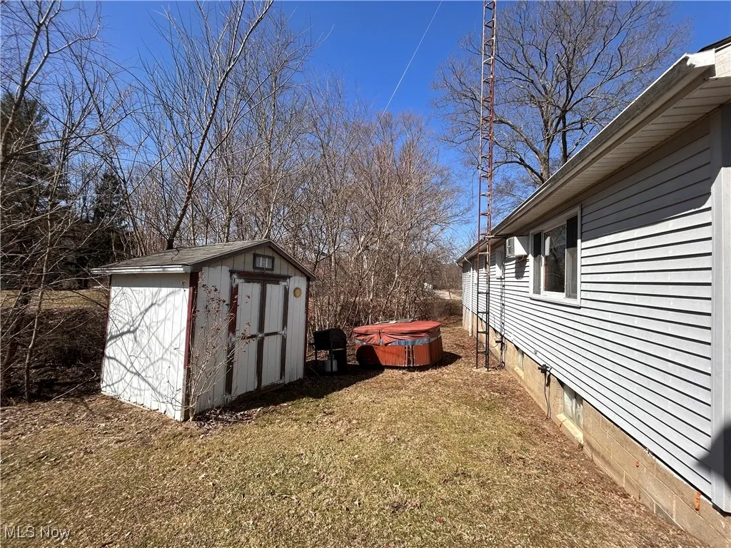View of yard featuring an outbuilding, a storage unit, and a hot tub