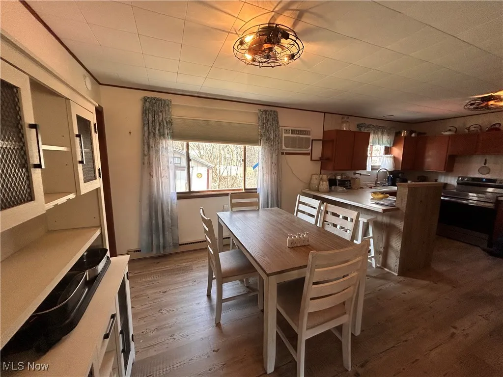 Dining room with dark wood finished floors, baseboard heating, and a wall mounted AC