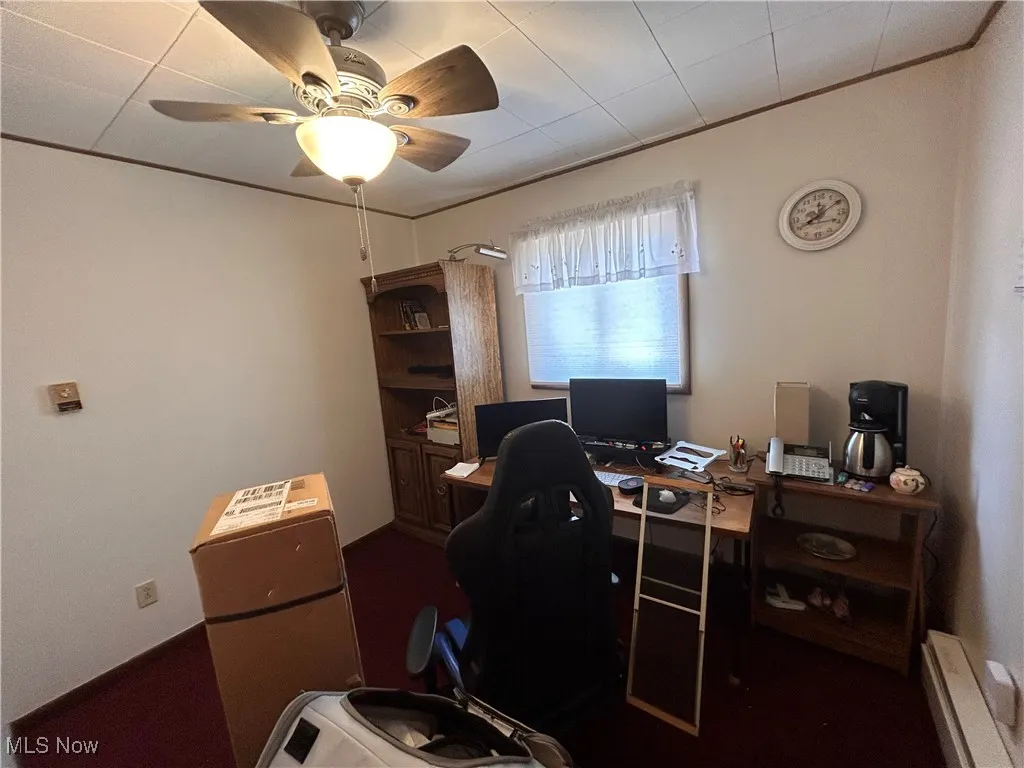 Office area with baseboard heating, ornamental molding, and a ceiling fan