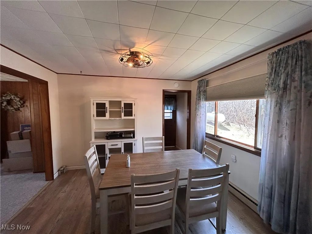 Dining area featuring baseboards, dark wood-type flooring, baseboard heating, and ornamental molding