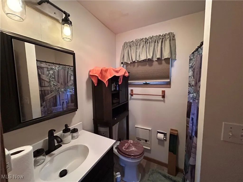 Bathroom with a shower with shower curtain, toilet, and vanity