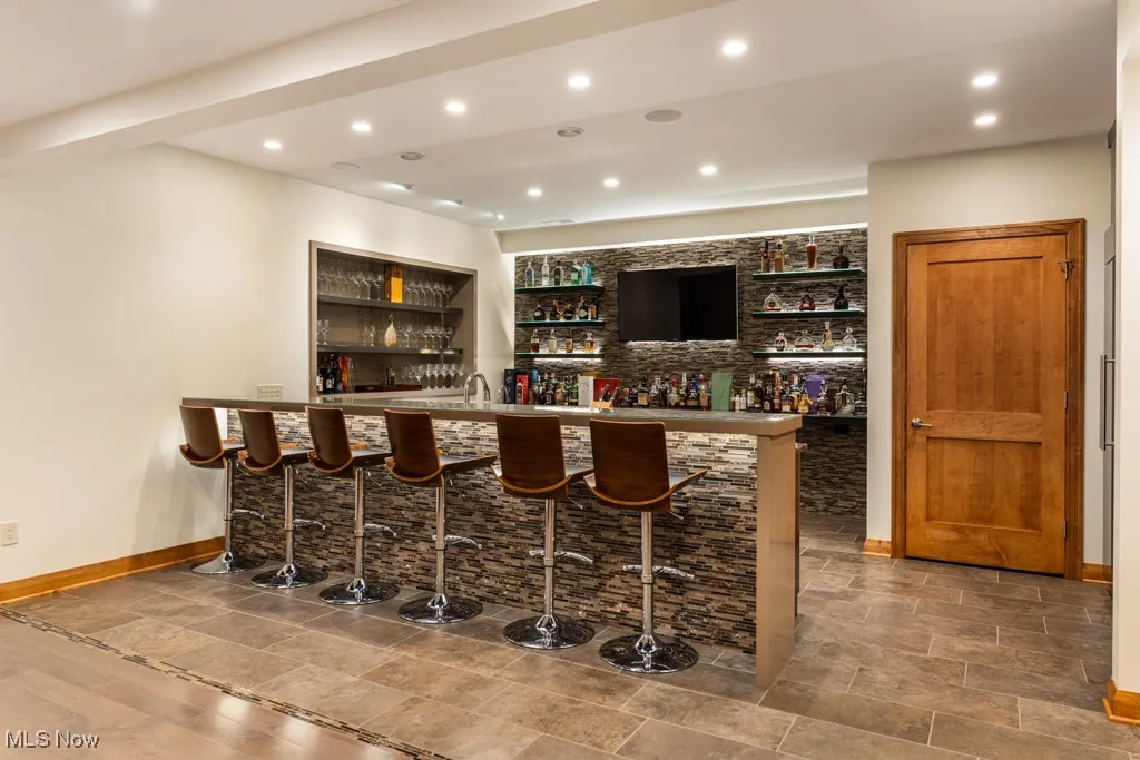 Bar featuring indoor wet bar, recessed lighting, and baseboards