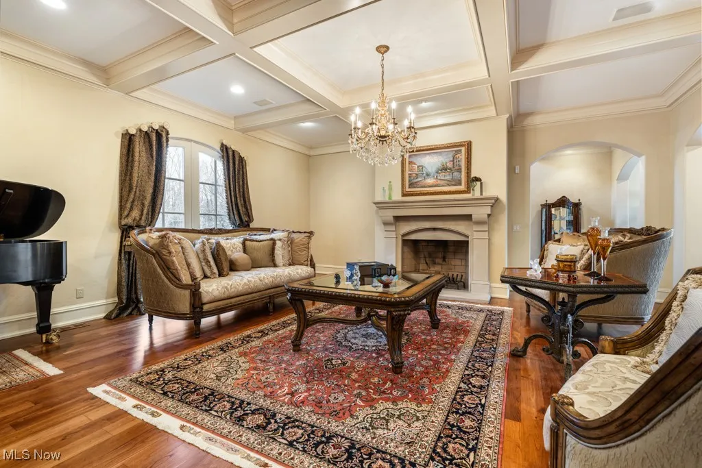 Living area with arched walkways, coffered ceiling, and wood finished floors