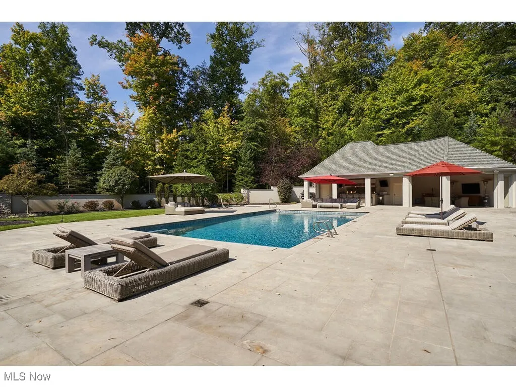 Outdoor pool with a storage structure, a patio, fence, a fire pit, and an outdoor structure