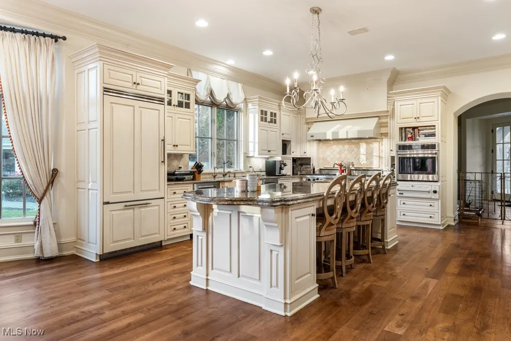 Kitchen featuring a center island, oven, extractor fan, a kitchen bar, and arched walkways