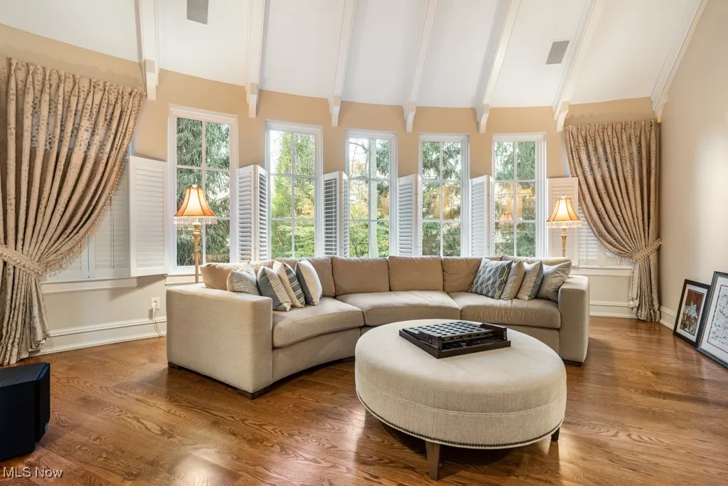 Living room with lofted ceiling with beams, baseboards, and wood finished floors
