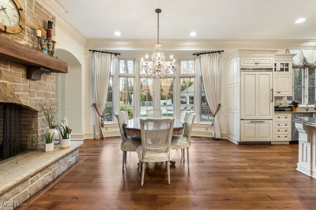 Dining room with dark wood finished floors, recessed lighting, an inviting chandelier, a fireplace, and crown molding
