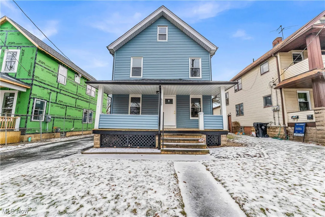American foursquare style home featuring a porch and fence
