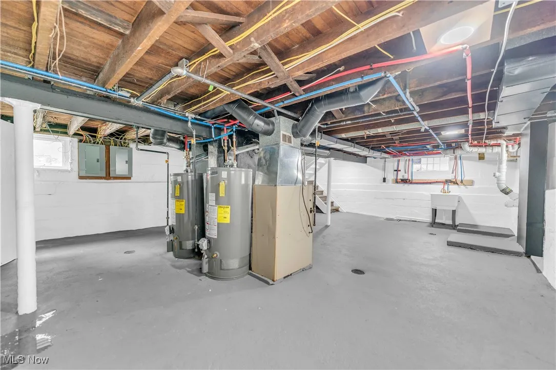 Below grade area featuring electric panel, gas water heater, and a sink