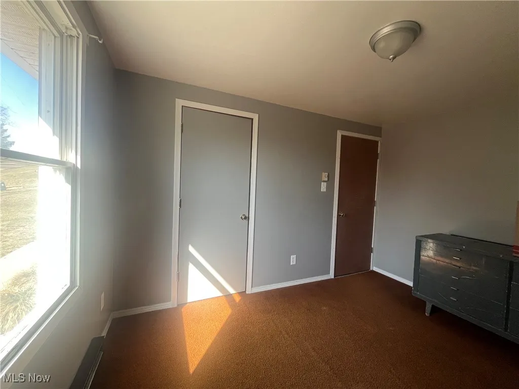 Unfurnished room featuring carpet and baseboards