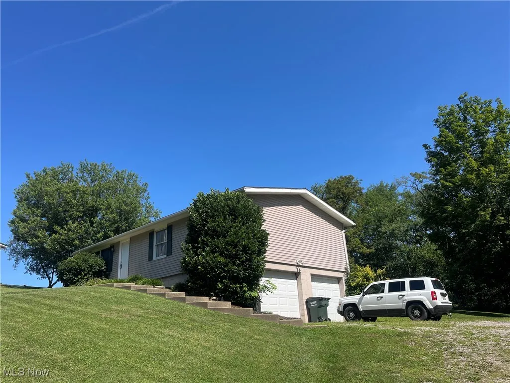 View of property exterior featuring an attached garage and a yard