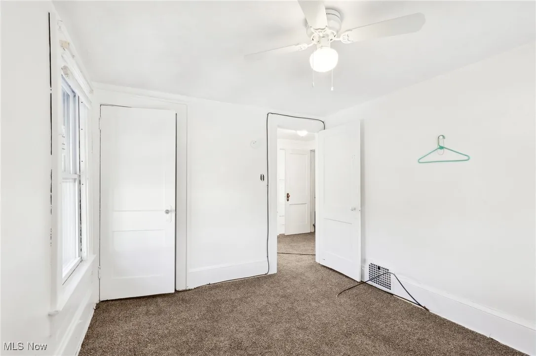 Unfurnished bedroom with baseboards, visible vents, carpet floors, and ceiling fan