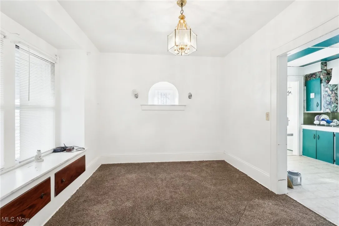 Unfurnished dining area with a notable chandelier, a healthy amount of sunlight, baseboards, and carpet floors