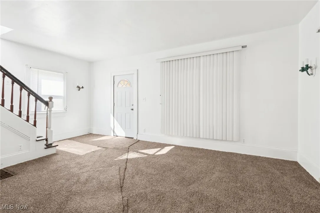 Foyer featuring stairway, baseboards, and carpet floors