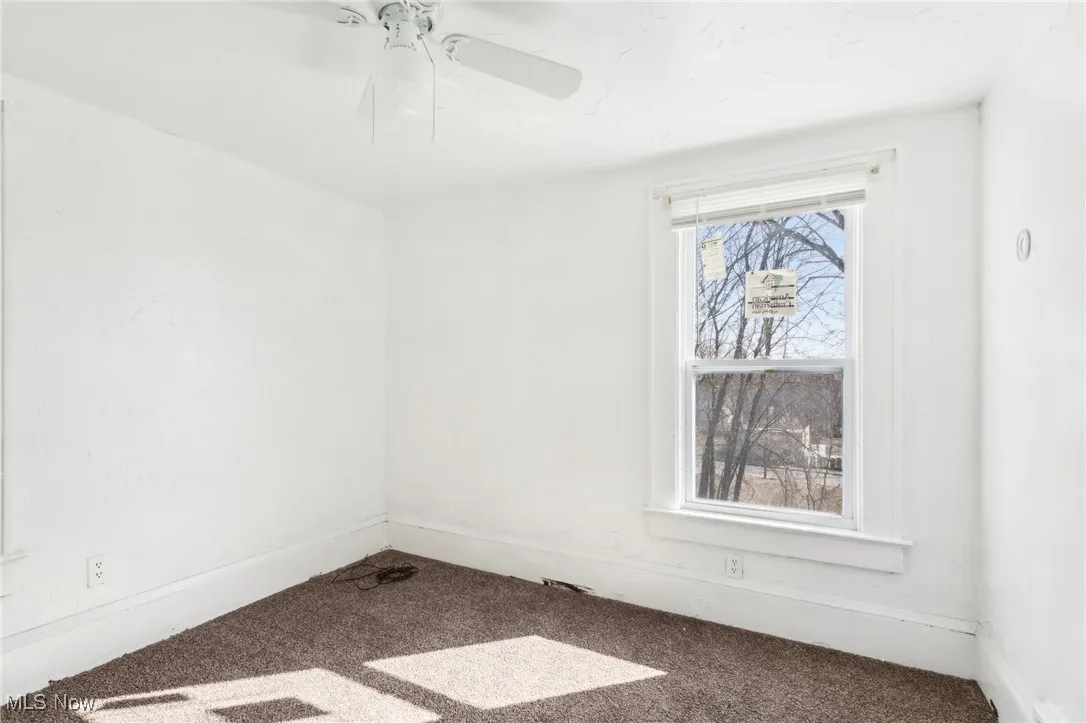Empty room featuring baseboards, ceiling fan, and carpet floors