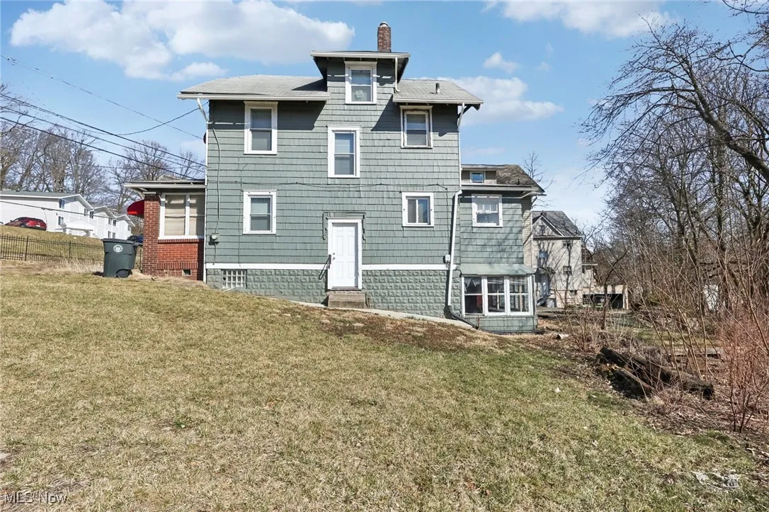 Rear view of house featuring a yard, fence, and a chimney