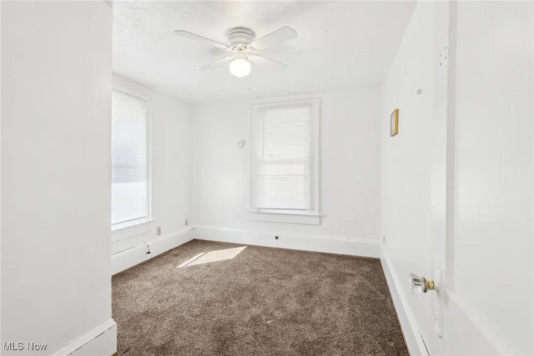 Empty room featuring carpet, baseboards, and ceiling fan