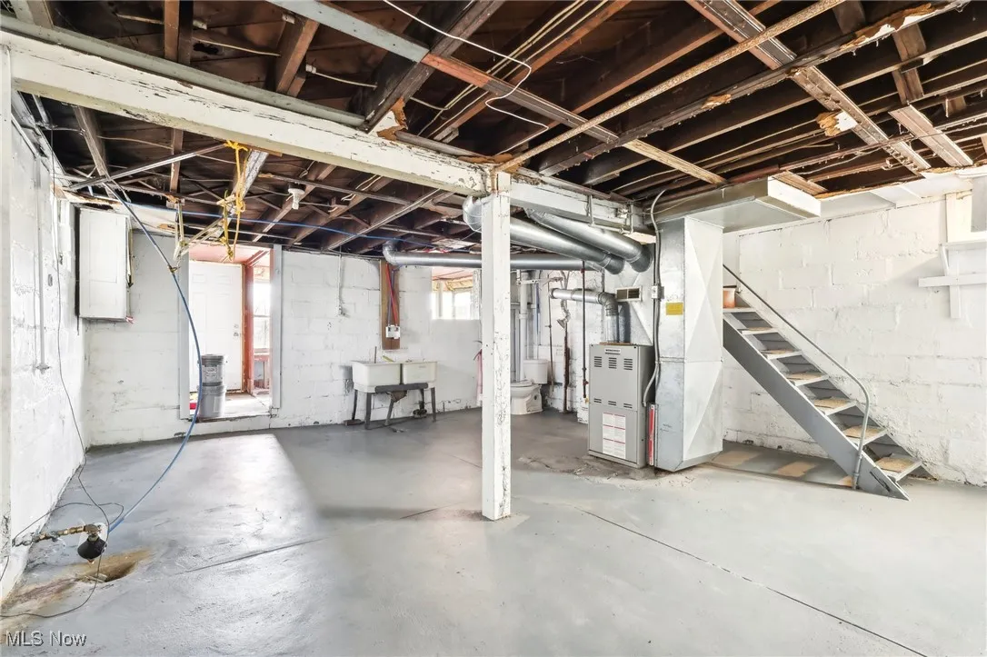 Below grade area with stairway, heating unit, and a sink