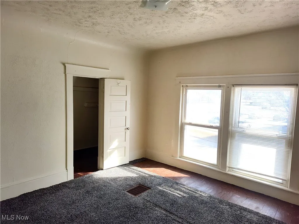 Unfurnished room featuring visible vents and a textured ceiling