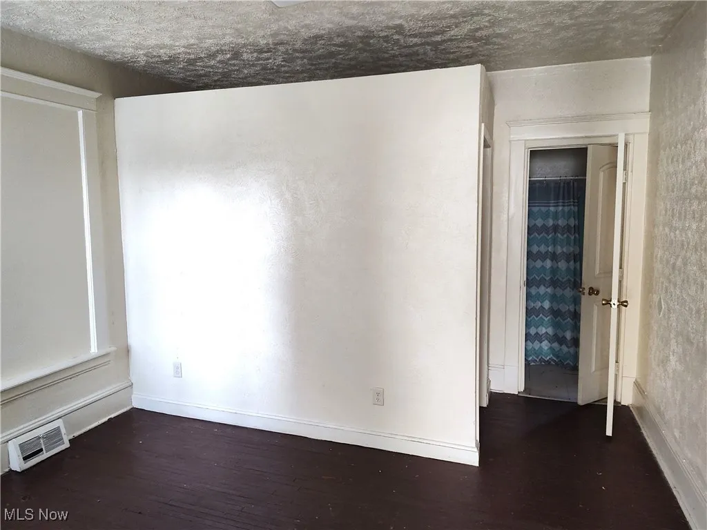 Spare room with visible vents, baseboards, and wood finished floors